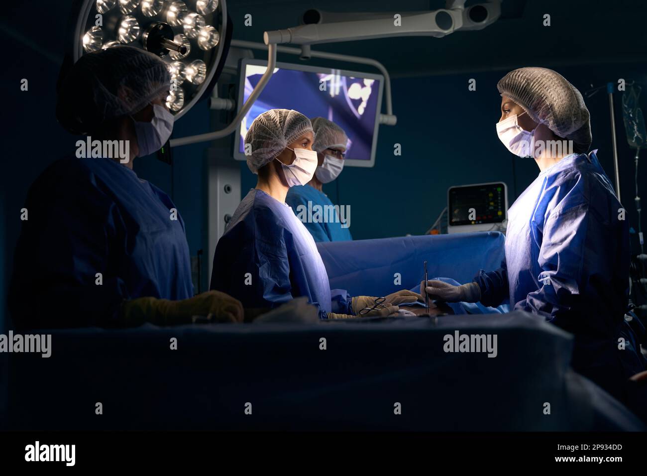 Team of surgeons in operating uniform stands at surgical table Stock ...