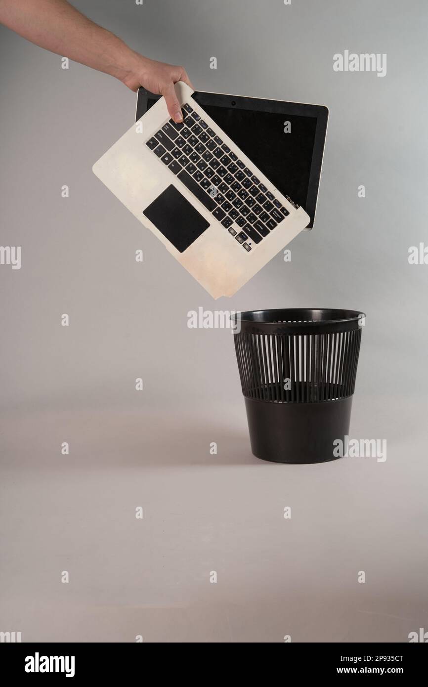 Electronic waste, broken or damaged, laptop in the trash, on a gray