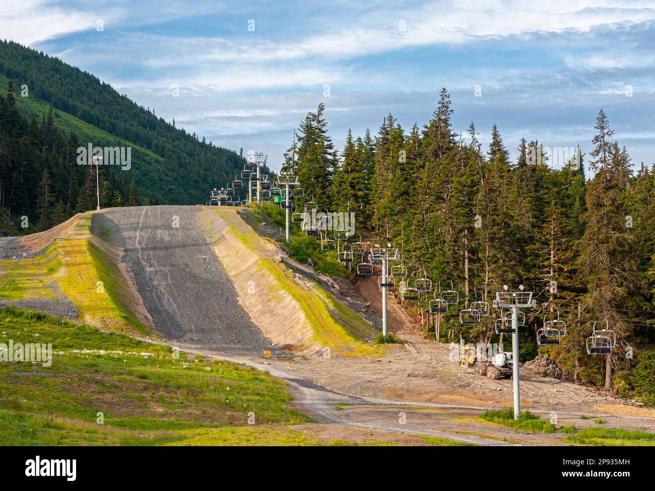 Girdwood Alaska, USA - July 23, 2011: Ski lift goes up the mountains from Alyeska Resort. Summer shows green trees, forested mountains, gray road, und Stock Photo