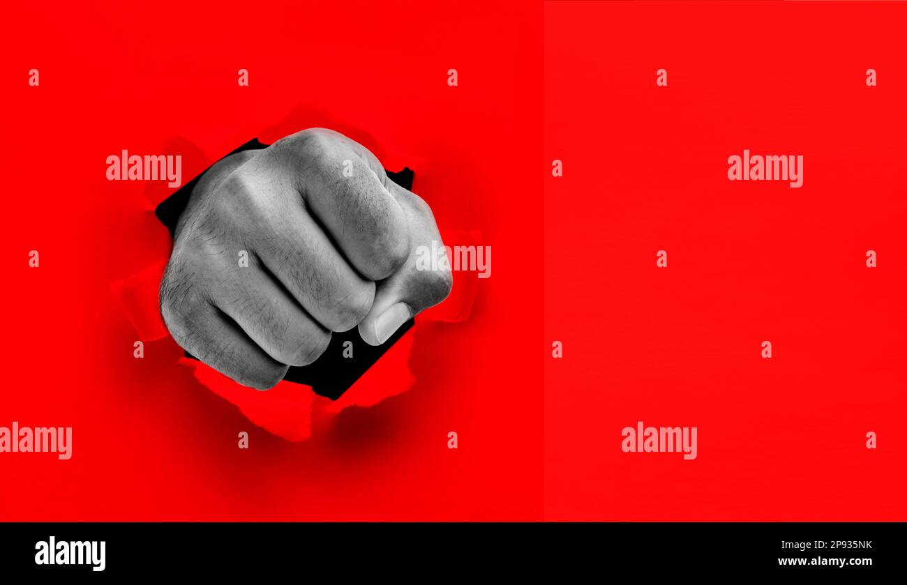 Fist punches through red paper Stock Photo