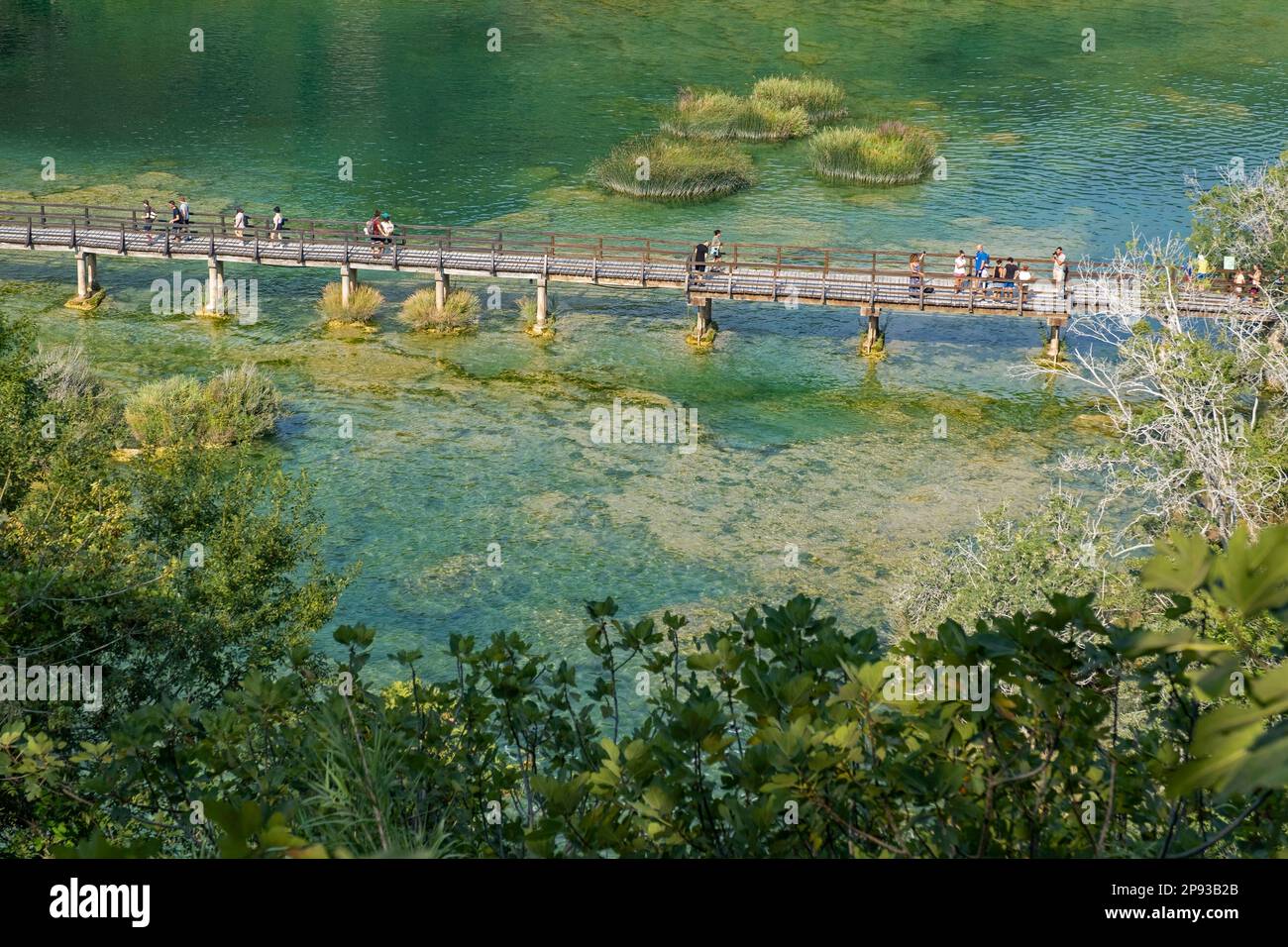 Tourists walking over wooden footbridge over pond in Skradinski buk at the Krka National Park near Šibenik, central Dalmatia, Šibenik-Knin, Croatia Stock Photo