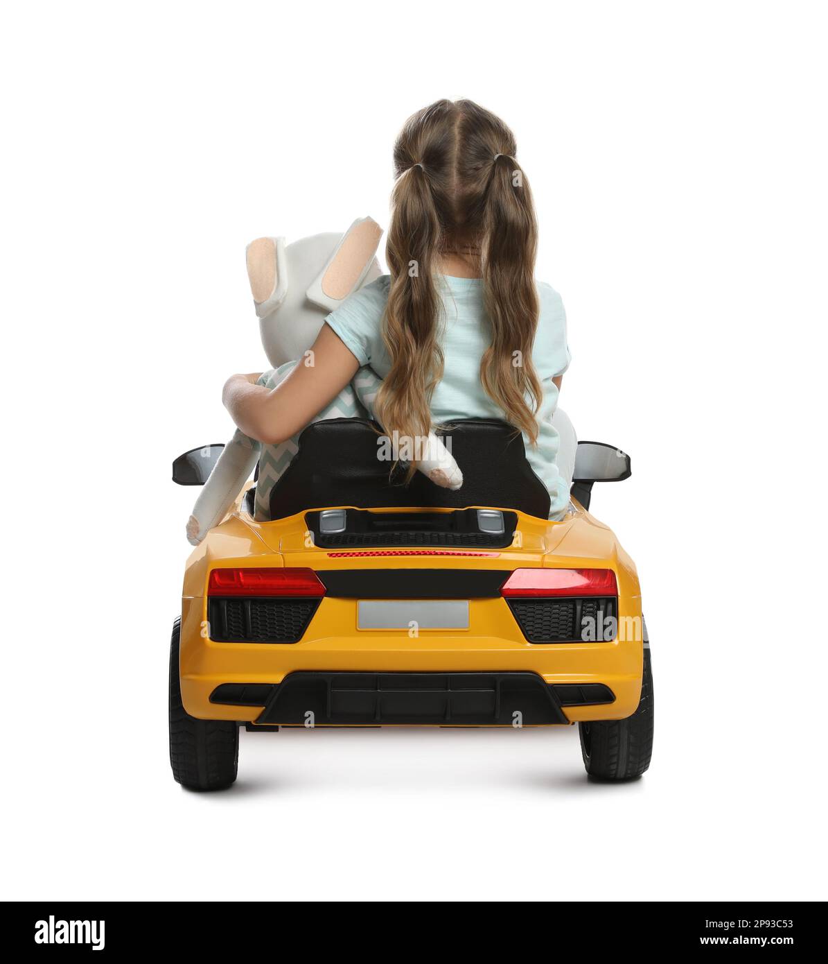 Cute little girl with toy bunny driving children's car on white background, back view Stock