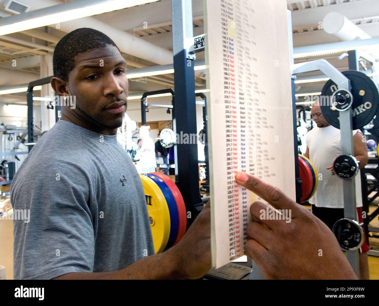 JMU alumni and Philadelphia Eagles linebacker Akeem Jordan checks the weight  conversion chart to determing the correct configuration of the weights  during his workout at the James Madison athletic complex in Harrisonburg,