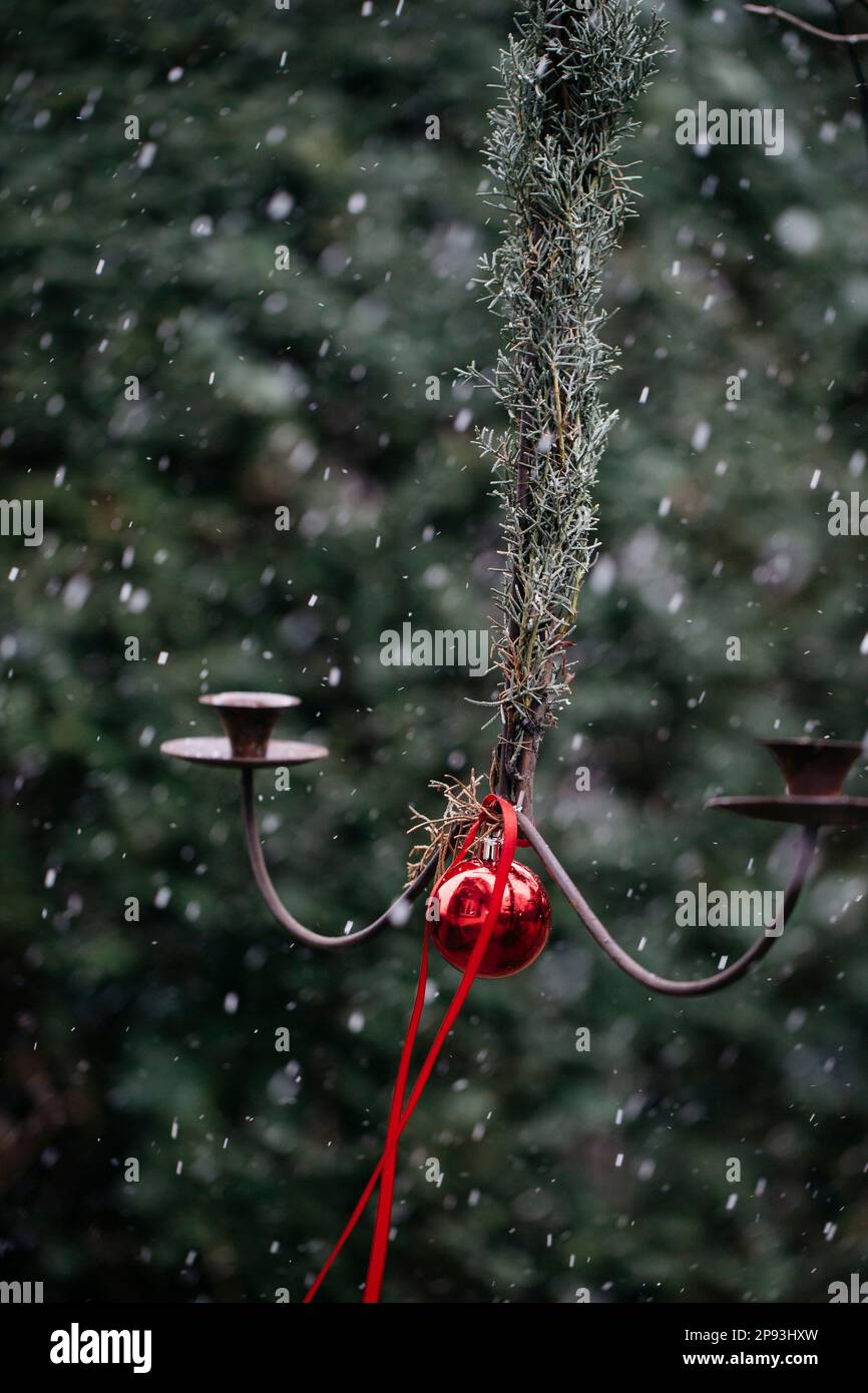 Hanging candle holder with a red Christmas tree ball in the snow flurry Stock Photo