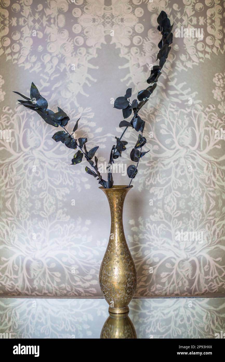 Golden flower vase with black branches on mirrored table Stock Photo