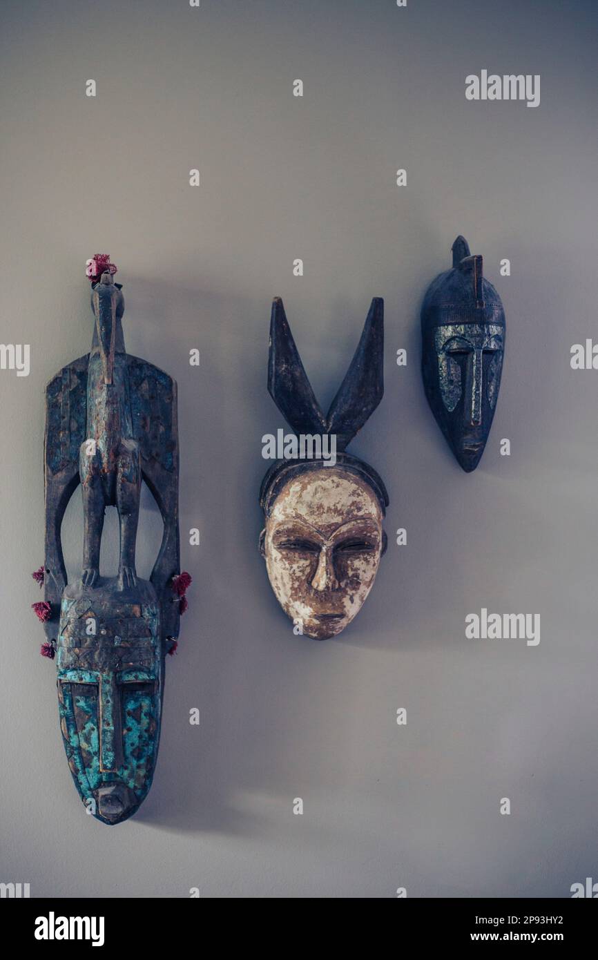 Three antique masks hang on a gray wall Stock Photo