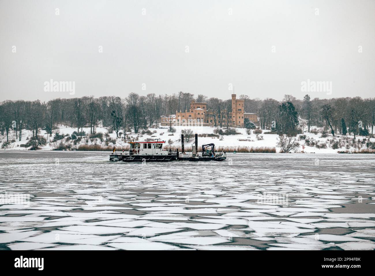 Germany, Brandenburg, Potsdam, view of Babelsberg castle from Glienicke bridge in winter with Havel river frozen over and icebreaker in foreground Stock Photo