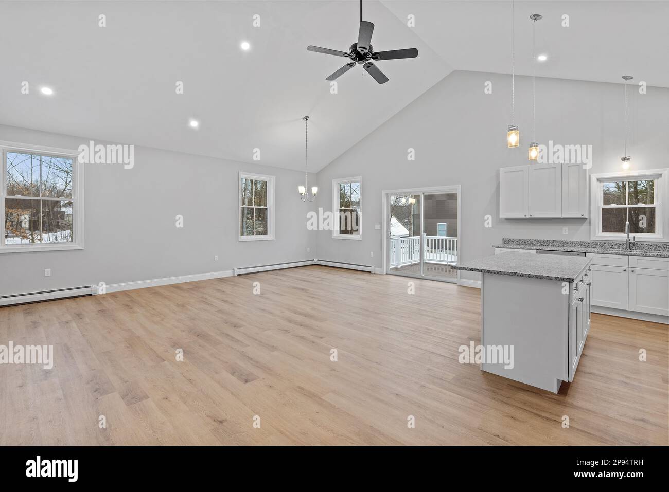 An empty kitchen with lots of white cabinets and a ceiling fan Stock ...