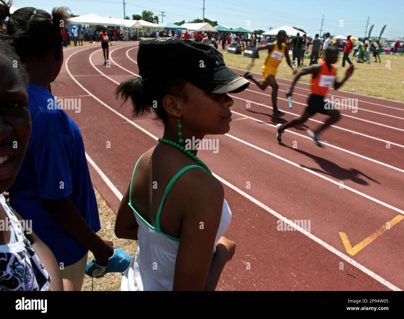 High School Age Track And Field Athletes Watch A 4x100 Relay While high-school-age-track-and-field-athletes-watch-a-4x100-relay-while