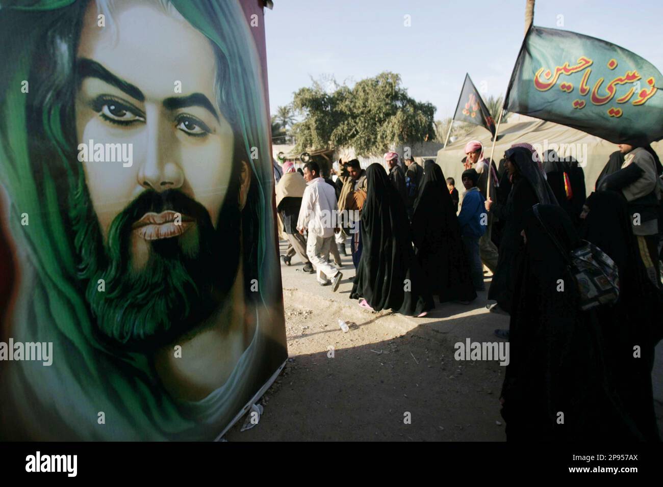 Pilgrims pass a poster showing Imam Hussein as they approach Karbala