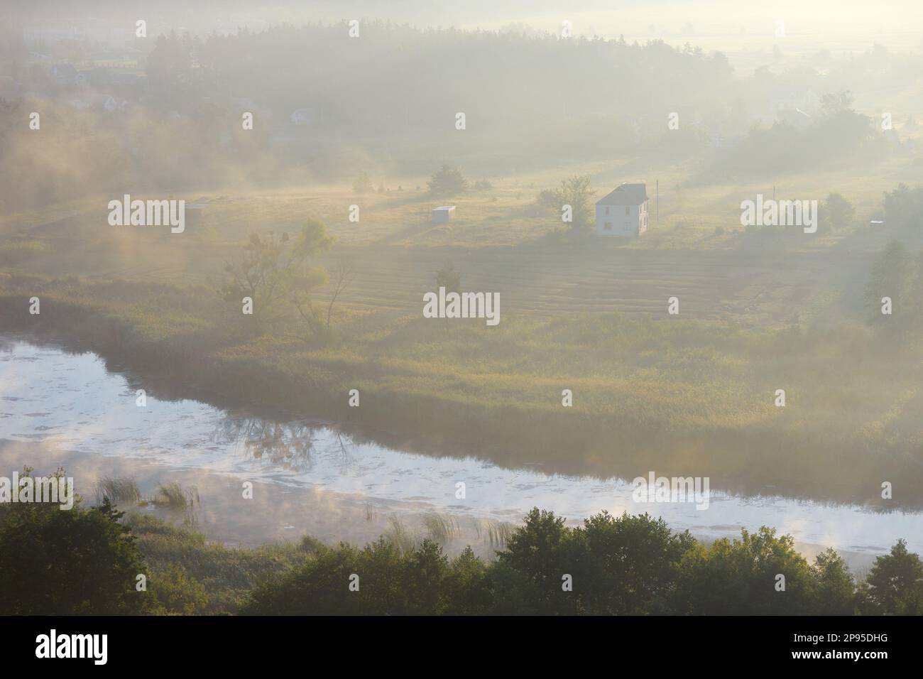 Summer landscape with a house in the fog. View from the hill. Morning mist over the river. Ukraine, Europe Stock Photo