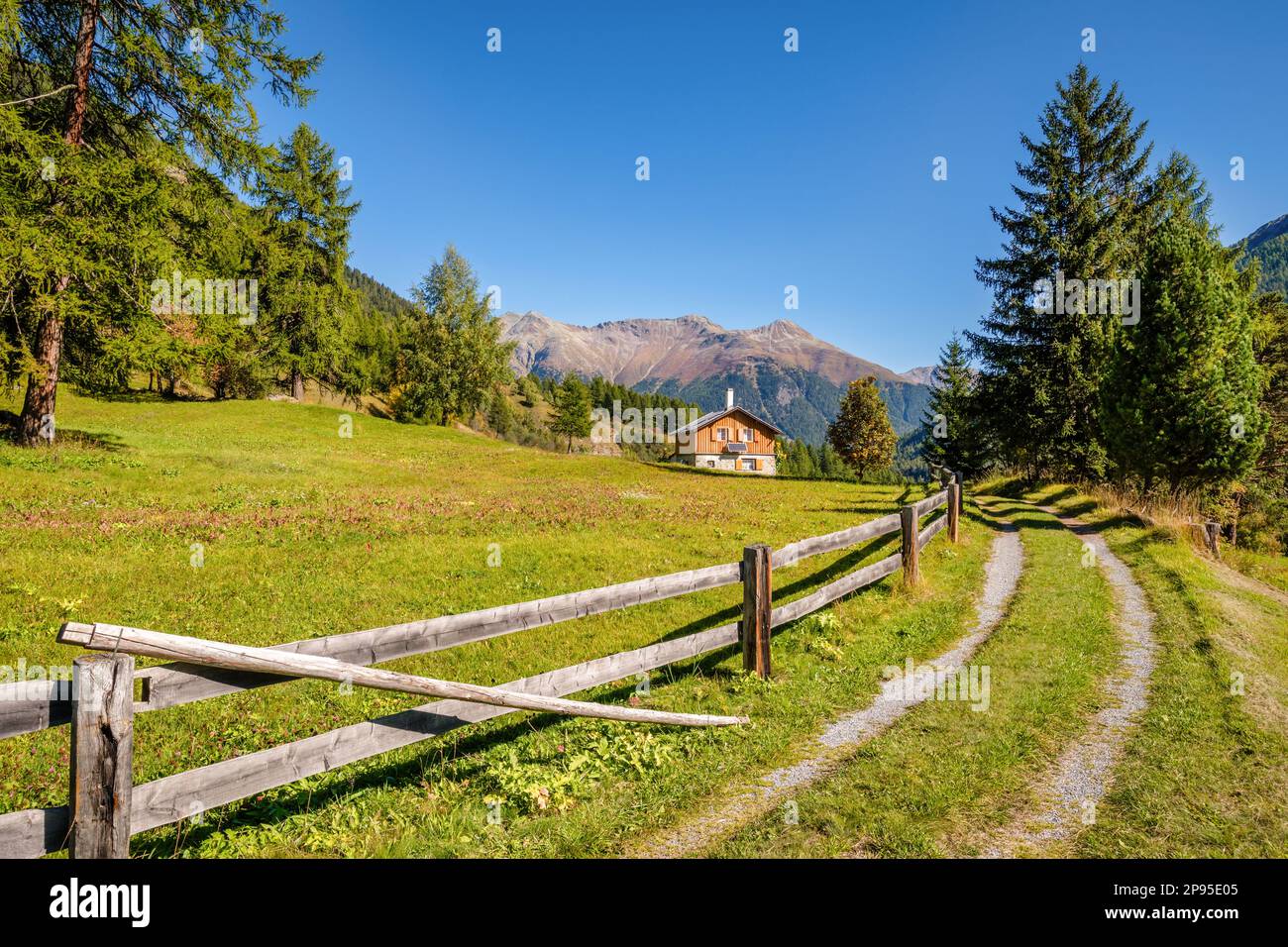 The autumn morning sun in September is shining on a lonely wood and stone house in the Upper Engadine Valley between the villages of Brail and Zernez. Stock Photo