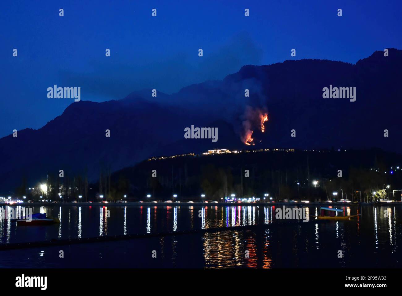 Flames and smoke rise behind the hotel during a forest fire in Srinagar. Stock Photo