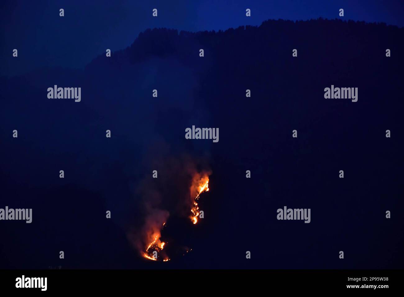 Flames and smoke rise from the Zabarwan hills during a forest fire in Srinagar. Stock Photo