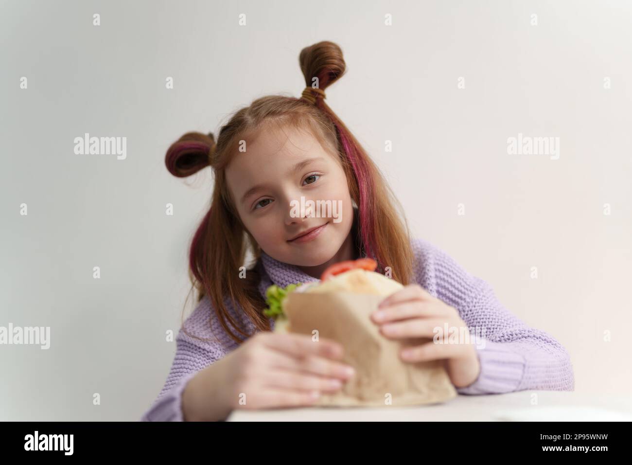 Cute little girl eats sandwich in fast food restaurant. Portrait of