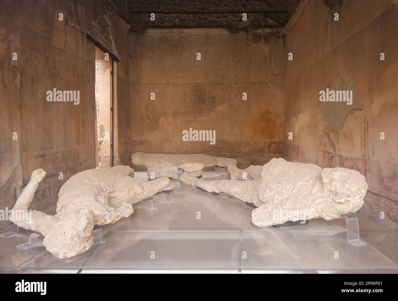 Plaster-encapsulated bodies of a slave and his owner on display at a house in Pompeii.  Pompeii was buried under meters of ash and pumice after the catastrophic eruption of Mount Vesuvius in 79 A.D. The preserved site features excavated ruins of streets and houses that visitors can freely explore. Stock Photo