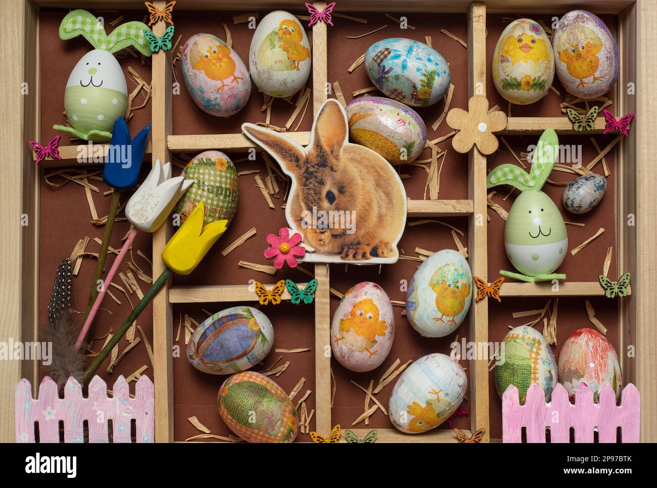 Creative festive wooden present box box with Easter decoration-Easter eggs, biscuits, bunnies, carrots, candies and festive symbols flat lay top view Stock Photo