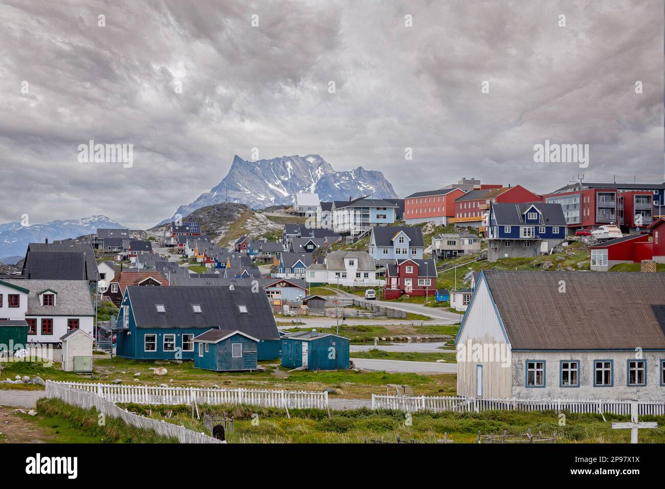 Many coloured houses set against a snow covered mountain backdrop in Nuuk, Greenland on 20 July 2022 Stock Photo