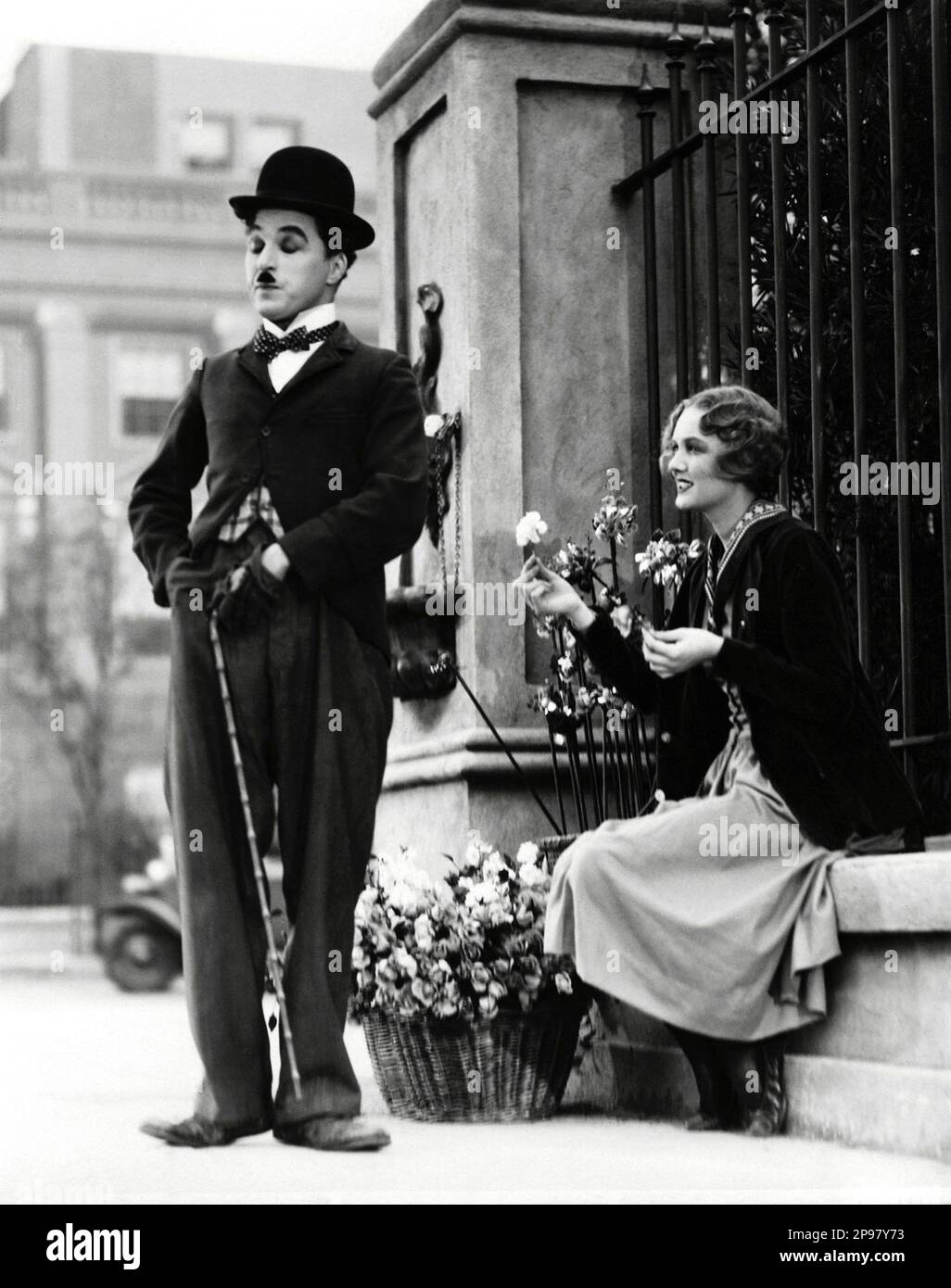 1931 : The silent movie actor and movie director CHARLES CHAPLIN ( 1889 - 1977 ) in CITY LIGHTS ( Luci della citta' ) with Virginia Cherrill - CINEMA MUTO  - FILM - candid - portrait - ritratto - regista cinematografico - attore - attrice - comico - fioraia - fleurist - fiorista - Charlot - bombetta - cappello - derby hat - flower - fiore - smile - sorriso - blind - cieca - cieco - ambulante ----   Archivio GBB      Archivio Stock Photo