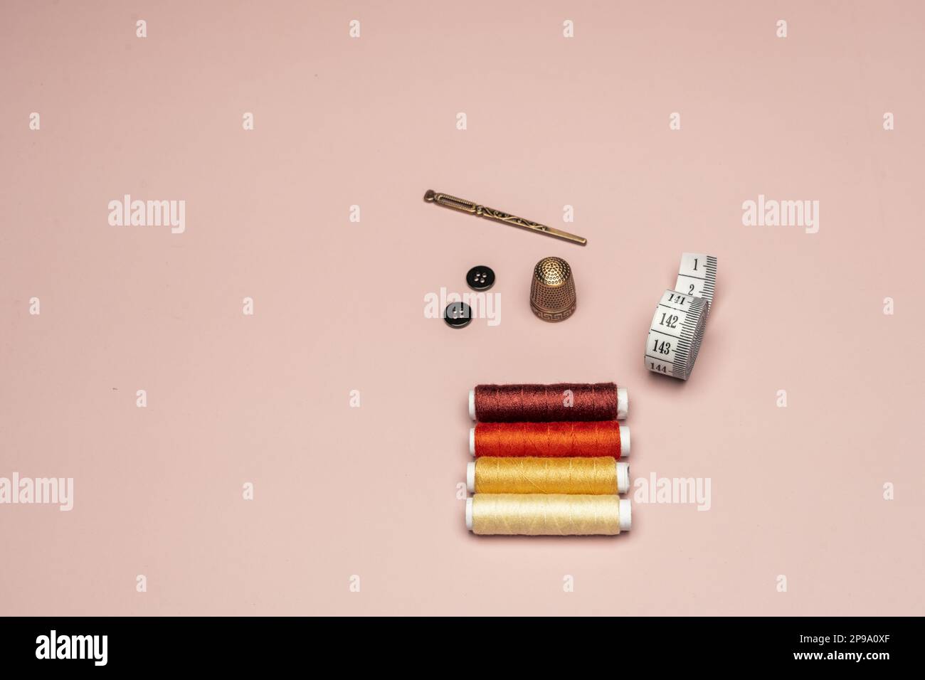 A copper thimble, a tape measure, spools of thread and a light pink ...