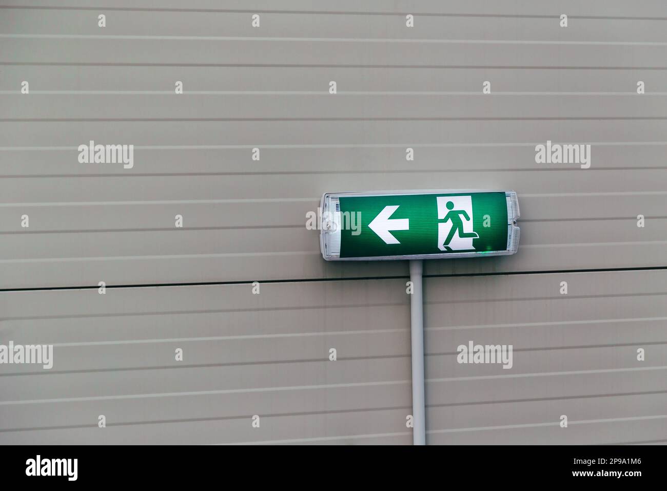 Emergency exit green sign on wall at emergency stairs at shopping center. Stock Photo