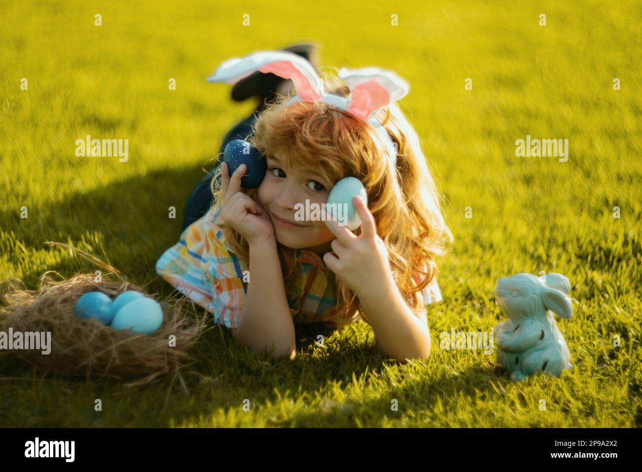 Child Rabbit Hunting Child hunt egg laying on grass in garden on Easter day. Kid boy with ...