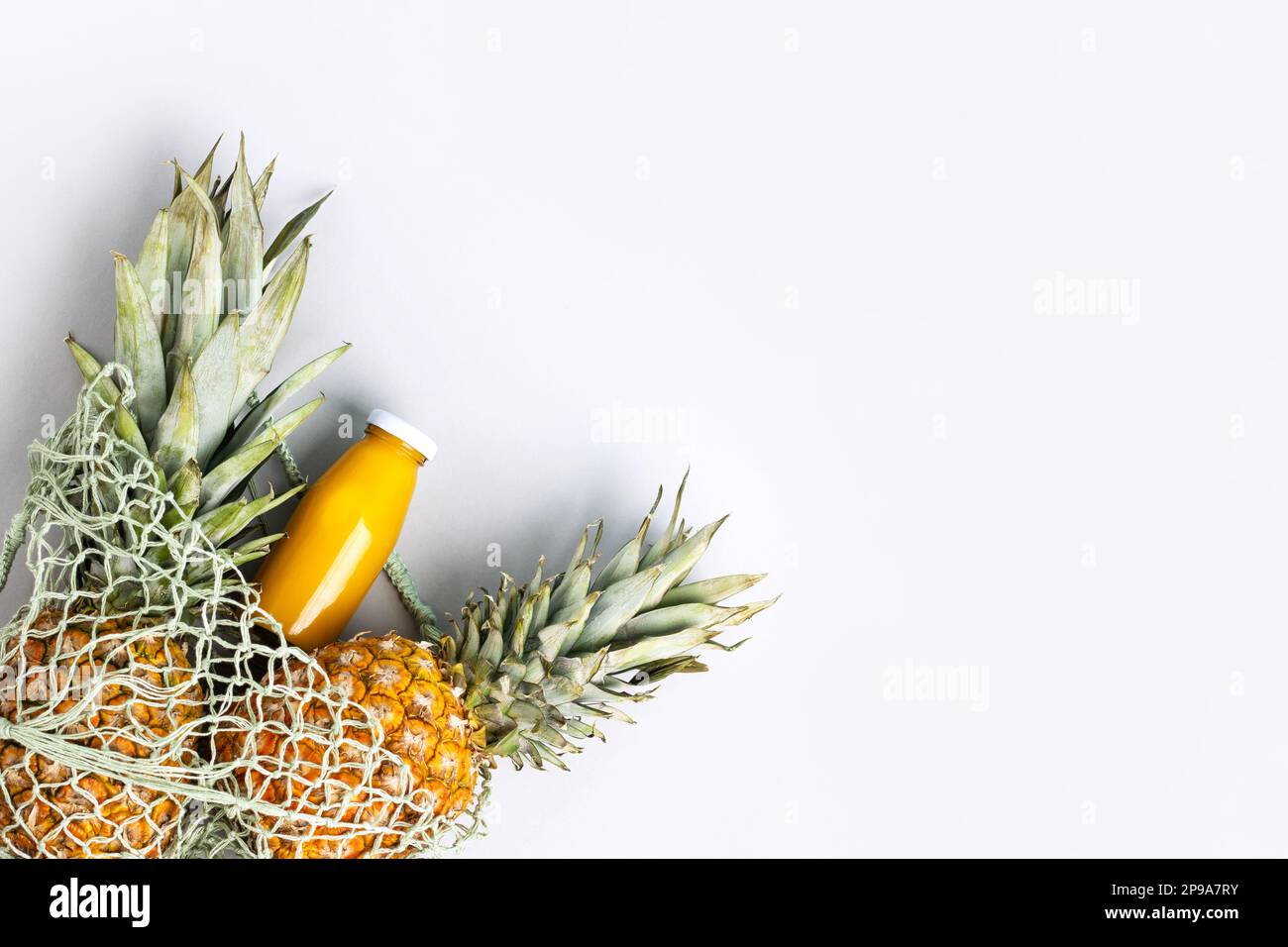 Two ripe juicy pineapples and natural fresh pineapple juice in a glass