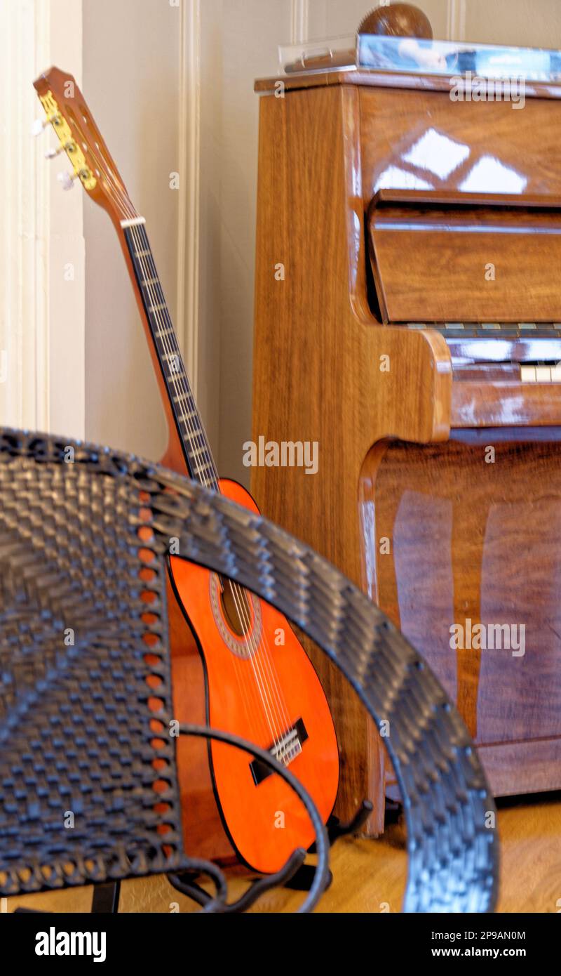Guitar, chair and a piano in the background in a vintage house in Alesund, Norway. 19th of July 2012 Stock Photo