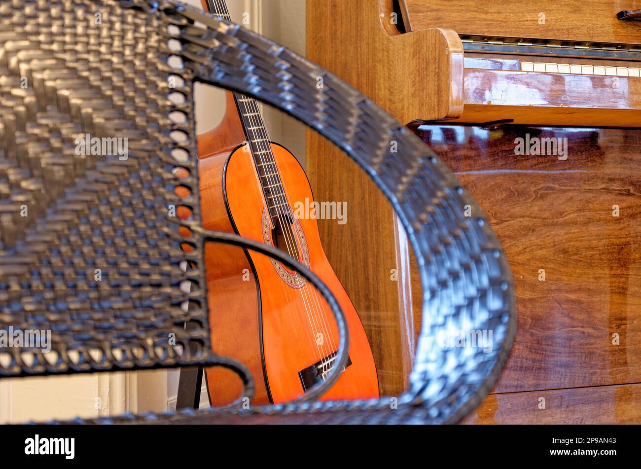 Guitar, chair and a piano in the background in a vintage house in Alesund, Norway. 19th of July 2012 Stock Photo