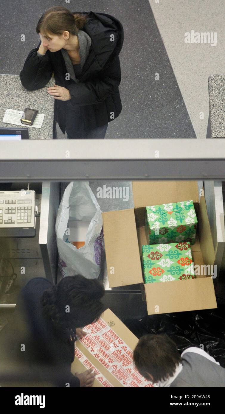 A passenger at an American Airlines ticket counter waits as her wrapped Christmas presents are