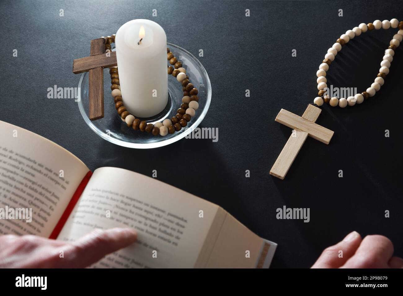 Christian believer reading bible on black nightstand with religious items for prayer with