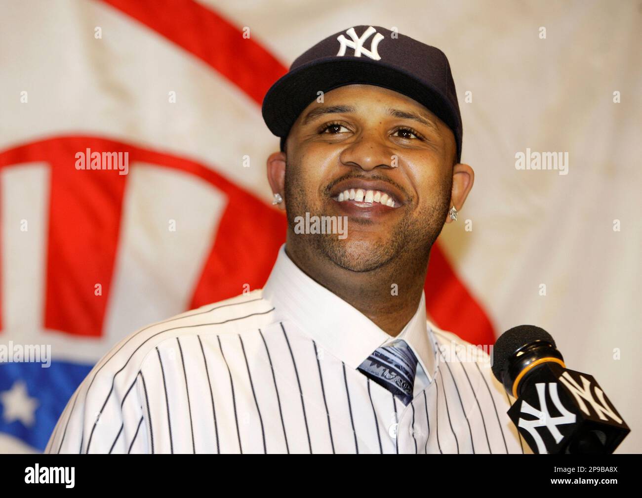 CC Sabathia smiles after donning a Yankee cap and uniform during a news
