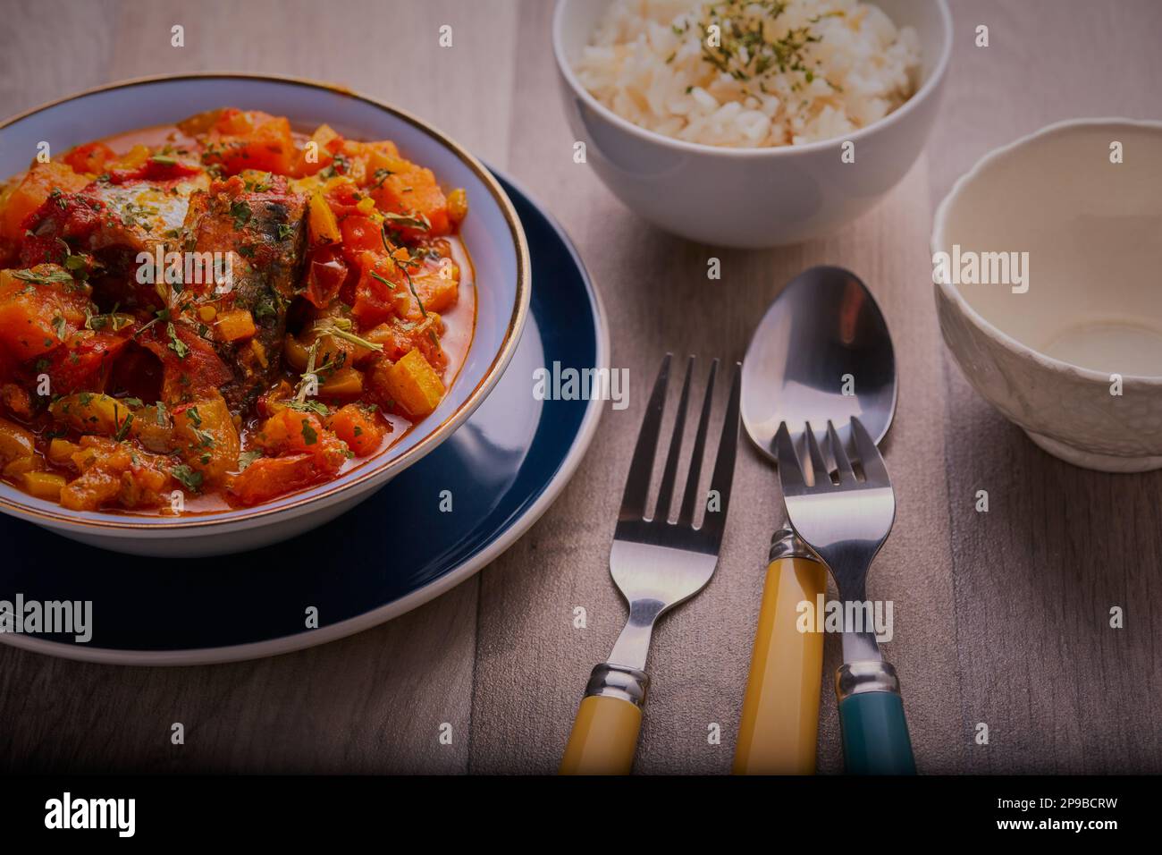 Asian fish curry with sweet potato and vegetables and a bowl of rice to accompany it. Stock Photo