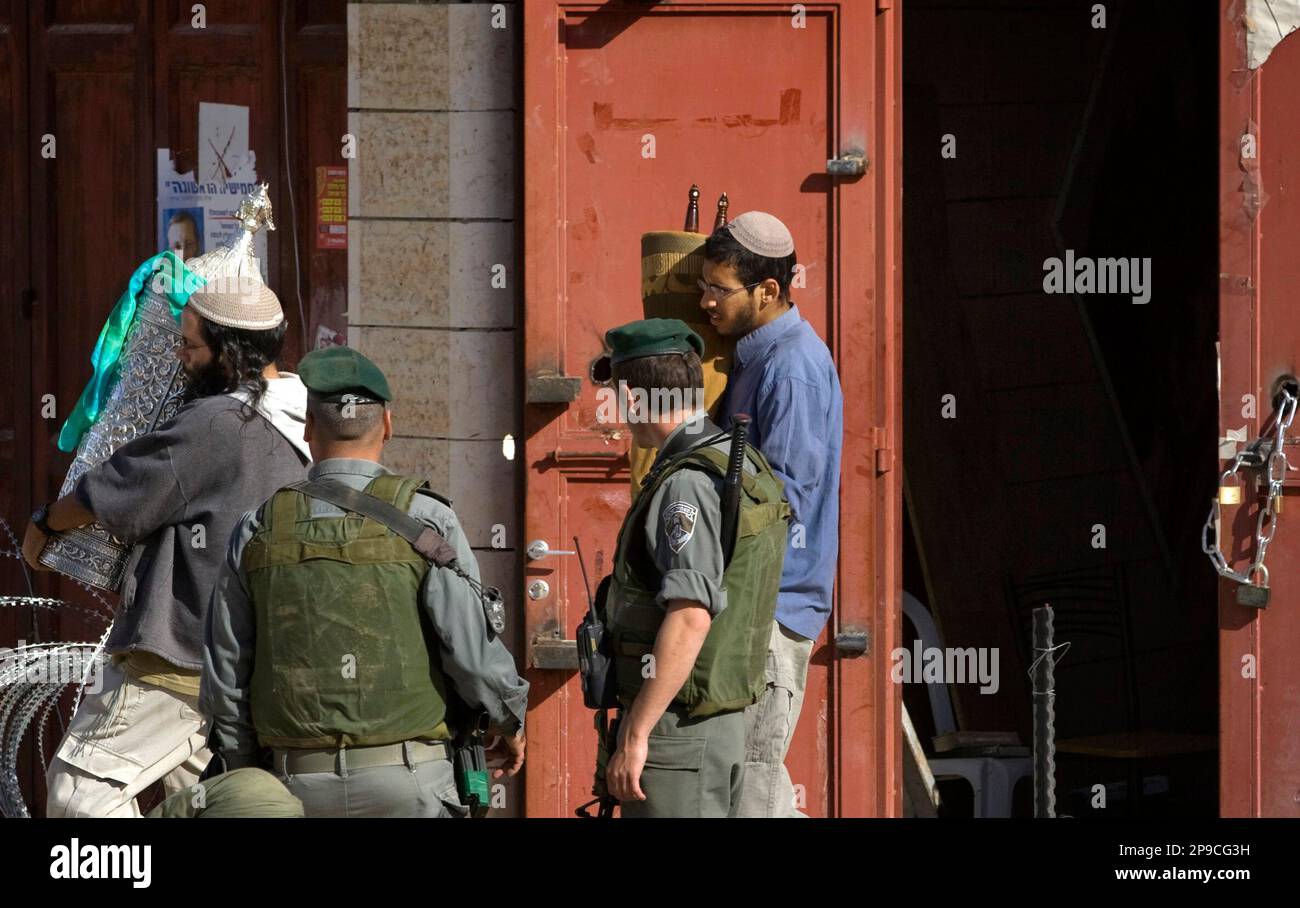 Israeli border police escort Jewish settlers as they carry Torah