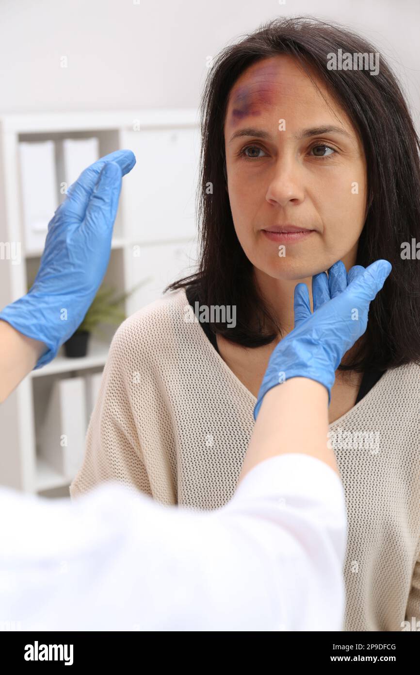 Doctor examining woman with bruise on forehead in clinic Stock Photo