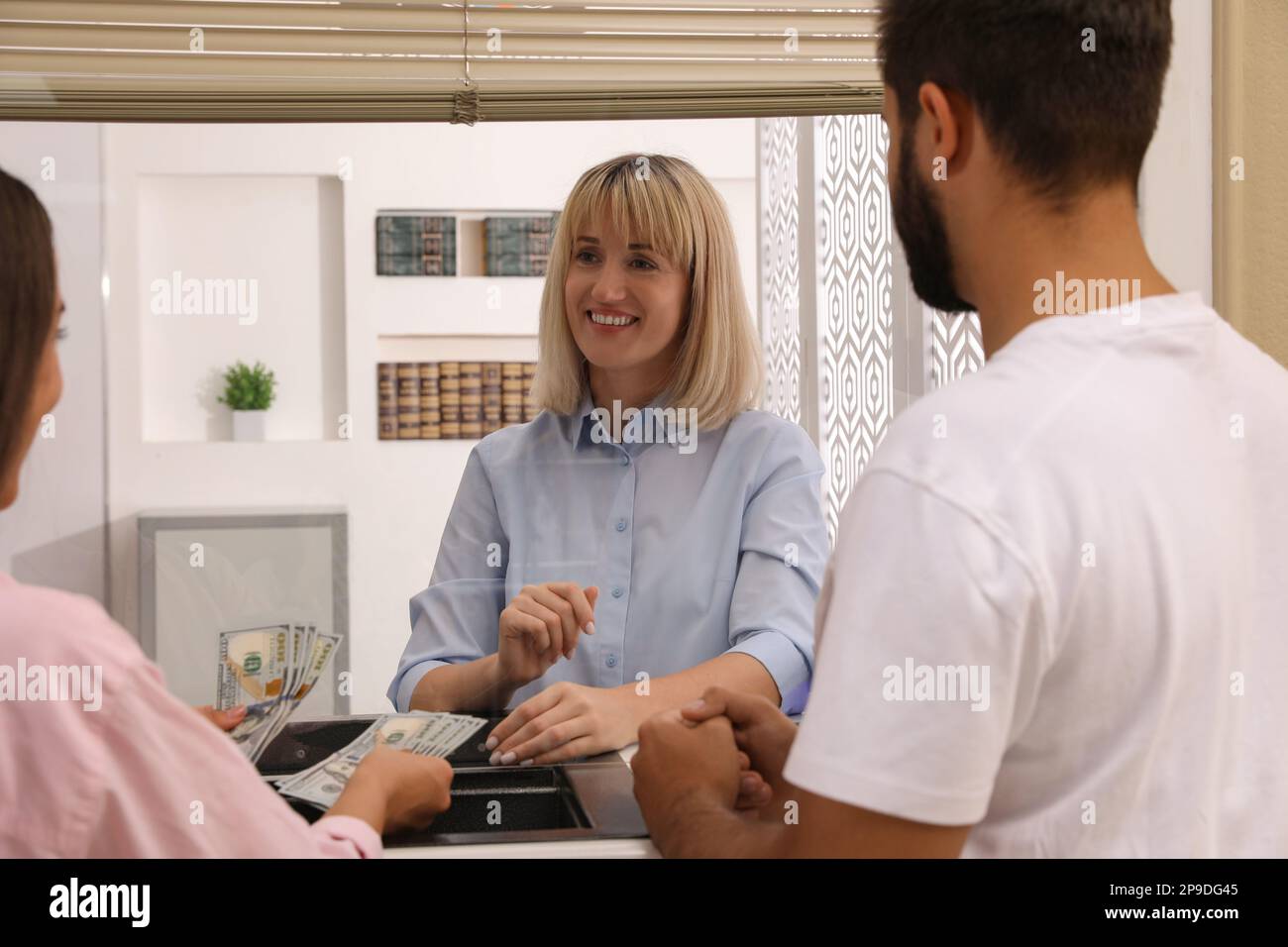 Couple with money at cash department window in bank. Currency exchange