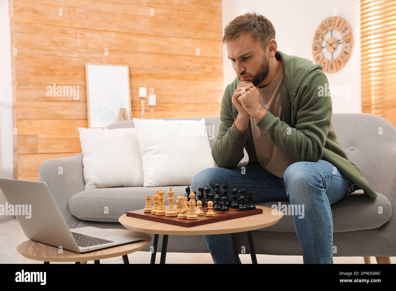 Young pensive man sitting and playing chess online