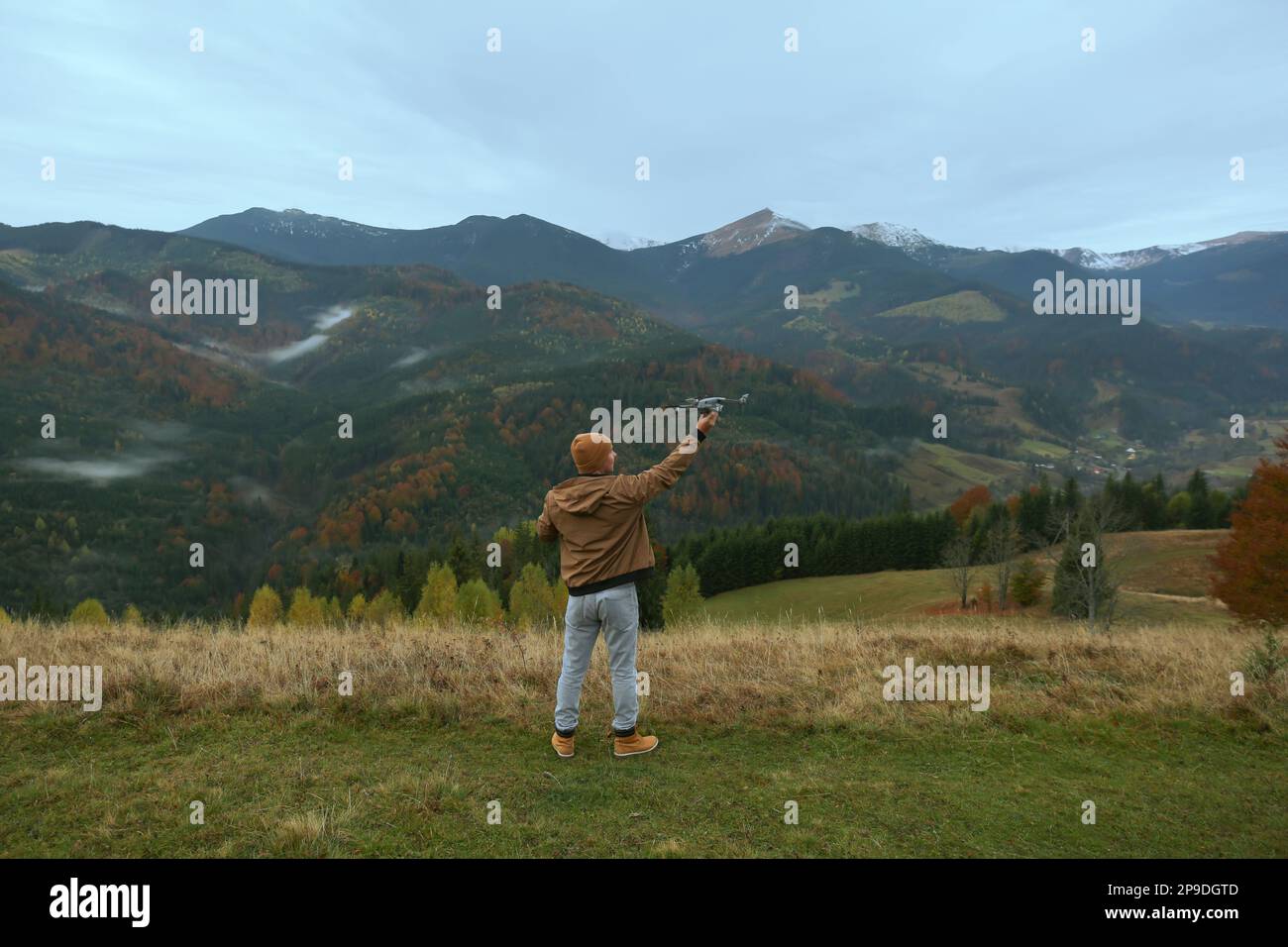 Young man with modern drone in mountains, back view Stock Photo