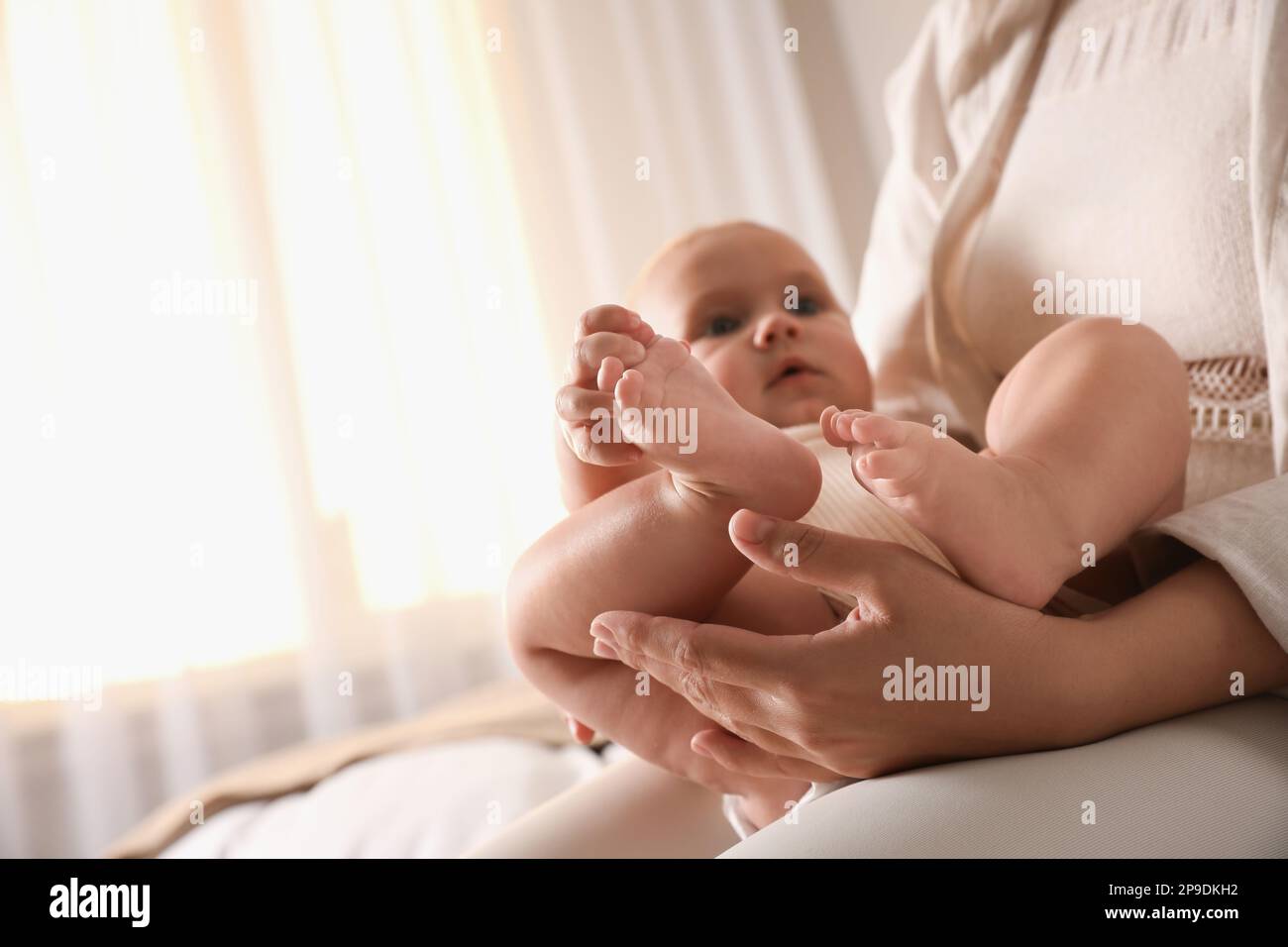 Young woman and her cute baby indoors, focus on feet. Lullaby songs Stock Photo