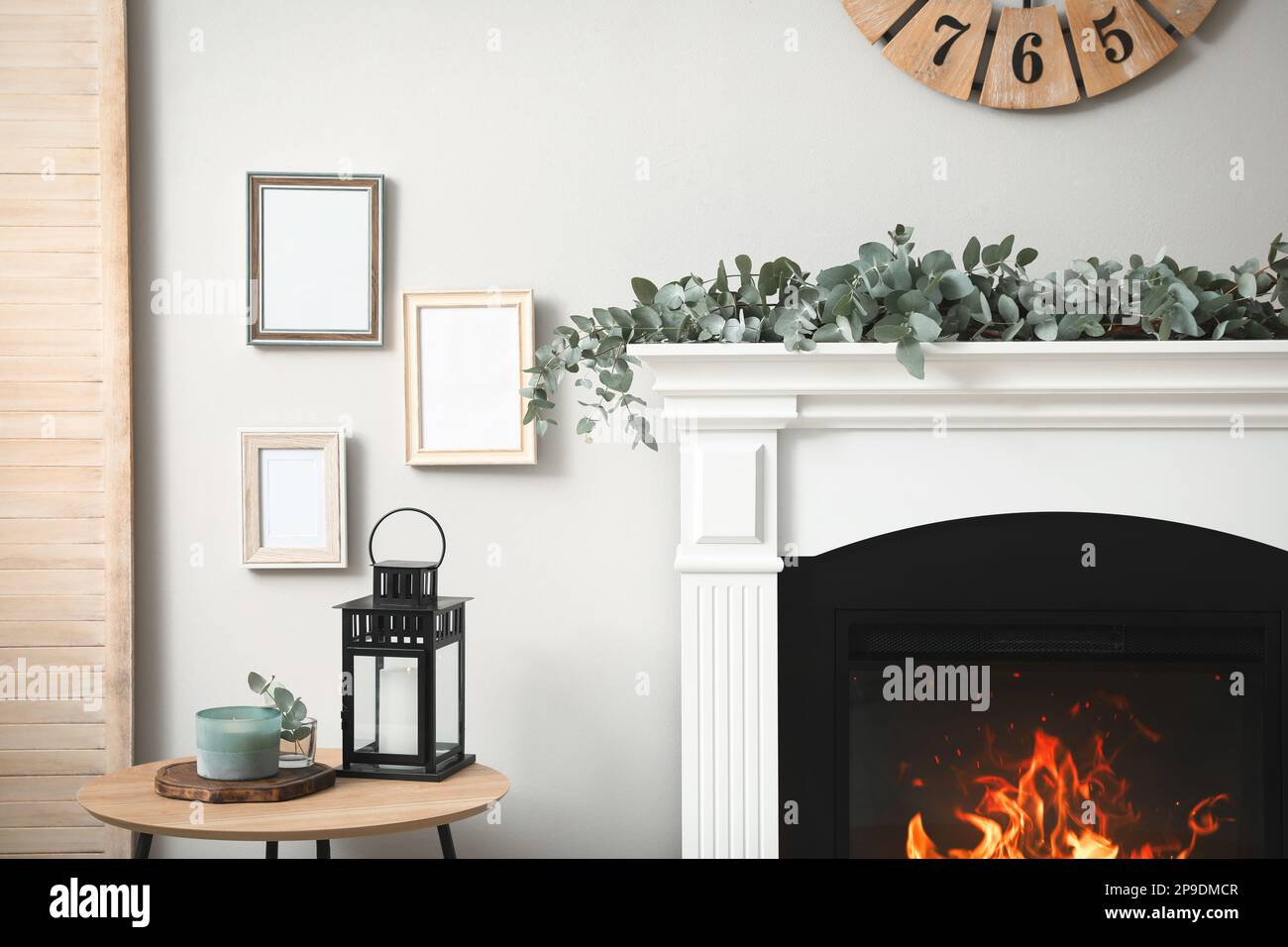 Beautiful garland with eucalyptus branches on fireplace in room Stock