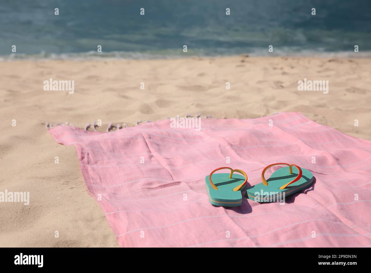 Pink striped beach towel and flip flops on sandy seashore Stock Photo ...
