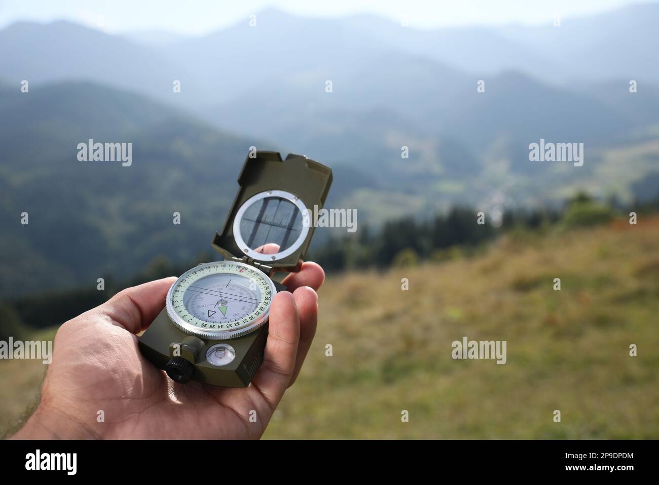 Man using compass during journey in mountains, closeup Stock Photo