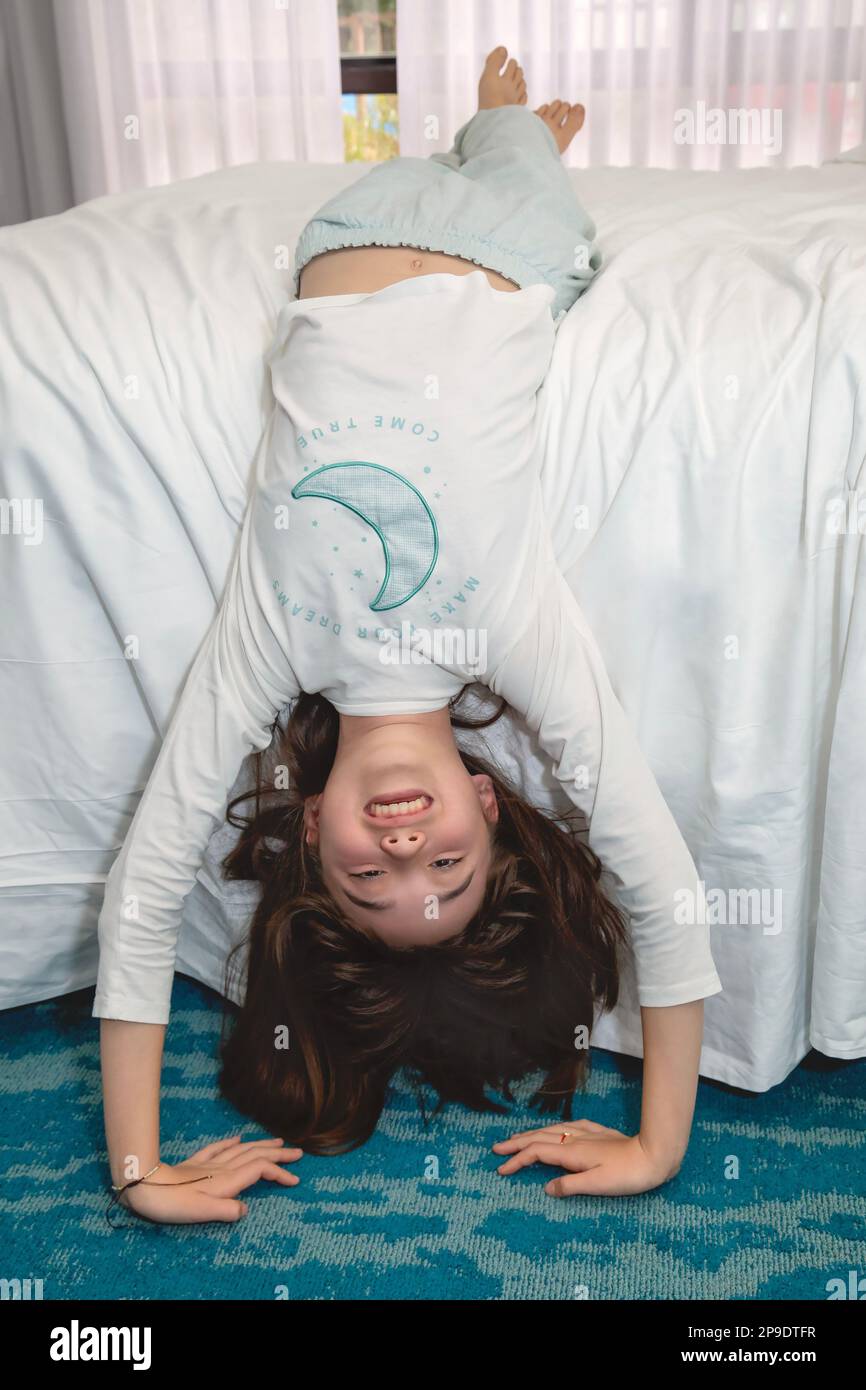 Eleven year old girl laying upside down from her bed Stock Photo