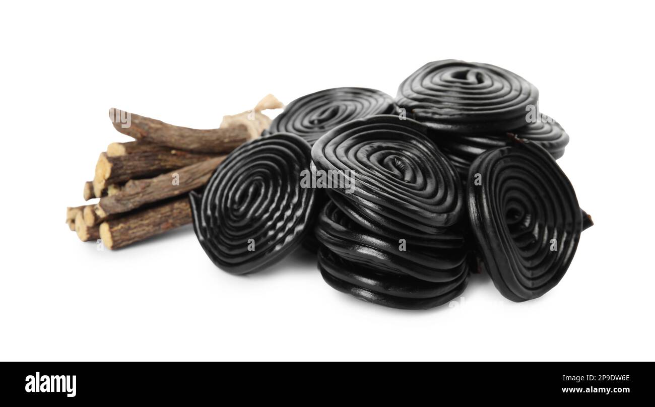 Tasty black candies and dried sticks of liquorice root on white
