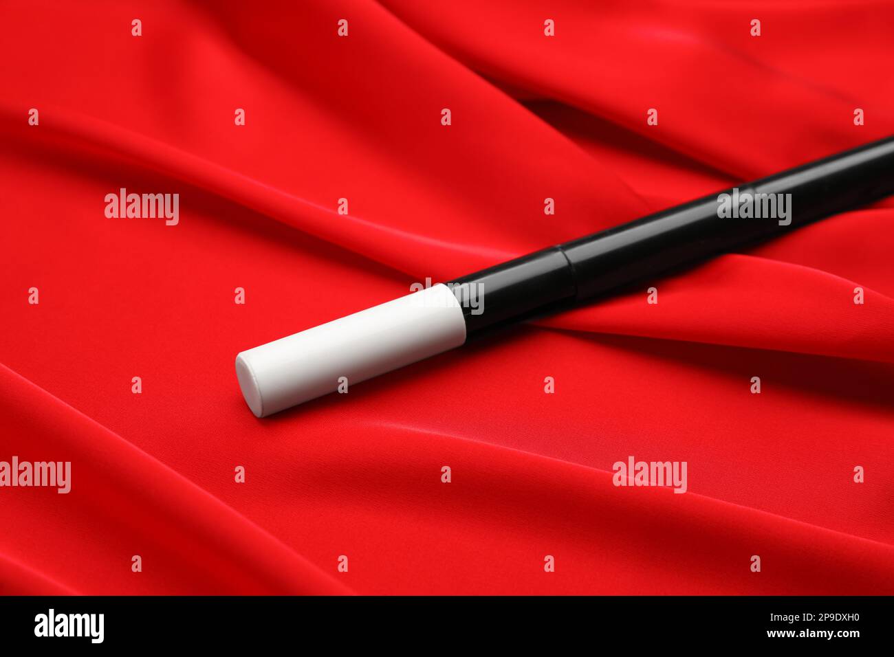 Beautiful black magic wand on red fabric, closeup Stock Photo