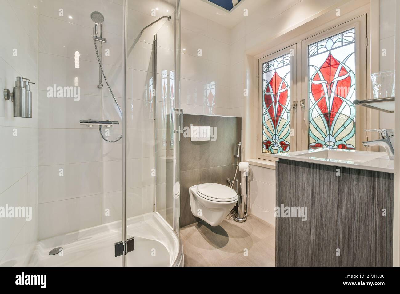 a bathroom with a stained glass window in the back wall and a white toilet next to the bathtub