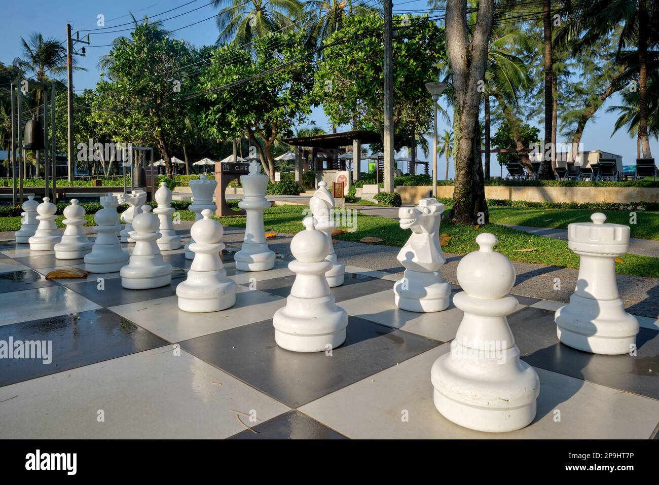 Large white chess figures on a giant chess board set up in front of exclusive Kata Noi Beach, Phuket, Thailand Stock Photo