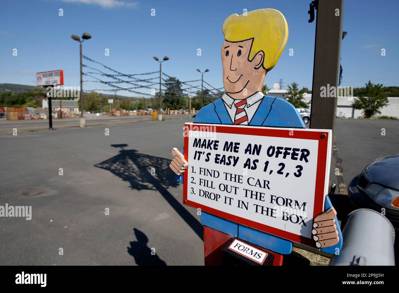 A cutout car salesman stands alone in a car lot at the closed Wilkes