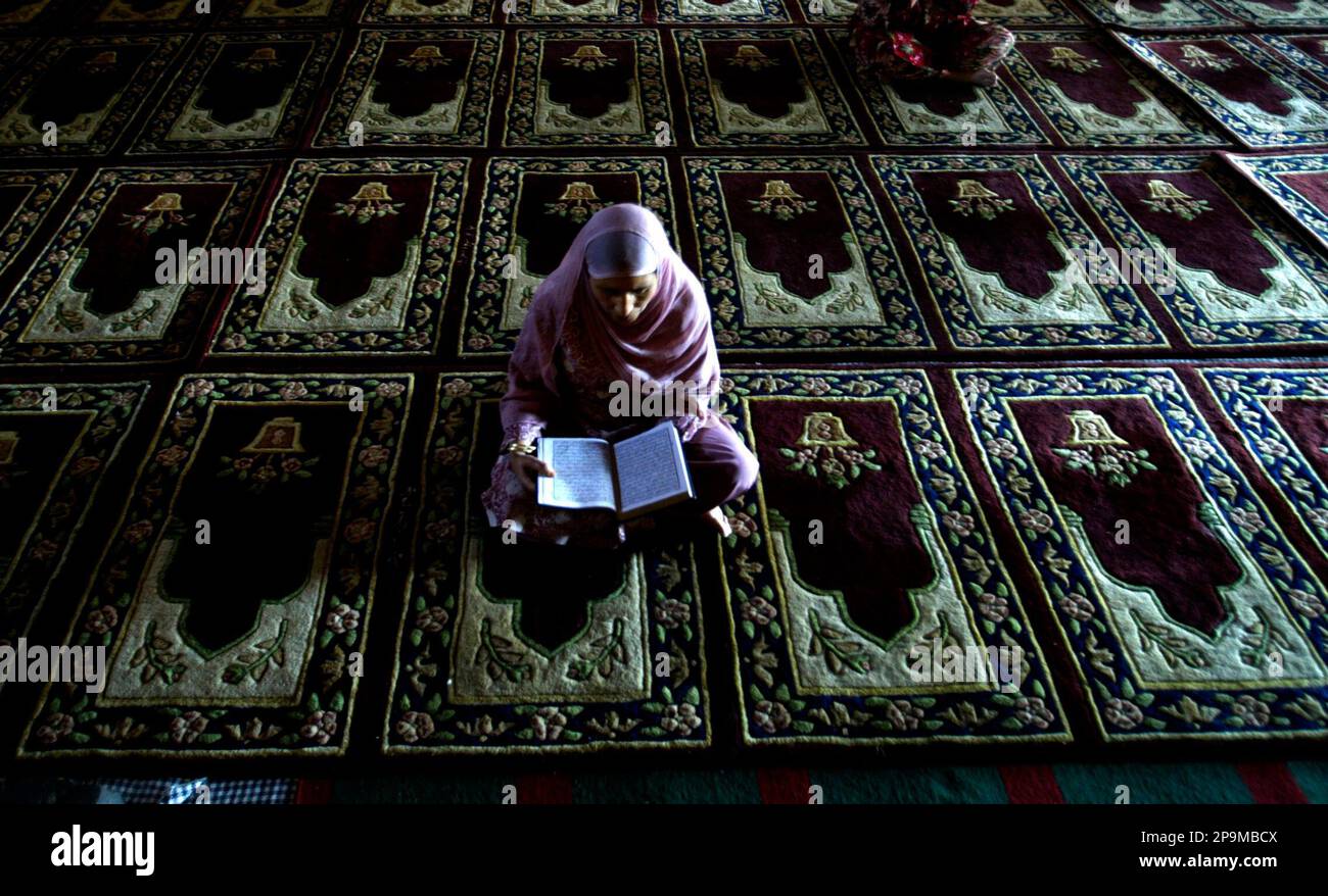 A Kashmiri Muslim woman recites holy Quran as she prays inside Jamia ...