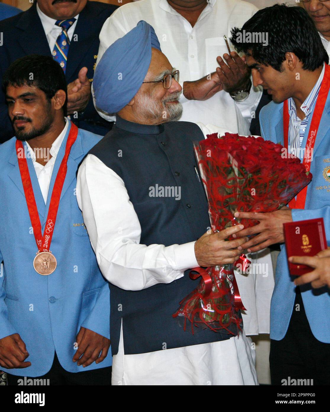 Indian Prime Minister Manmohan Singh, gifts a bouquet of flowers to Indian  boxer Vijender Kumar, right, as wrestler Sushil Kumar,left, looks on, in  New Delhi, India, Tuesday, Aug. 26, 2008. Sushil and, image size:1115x1390